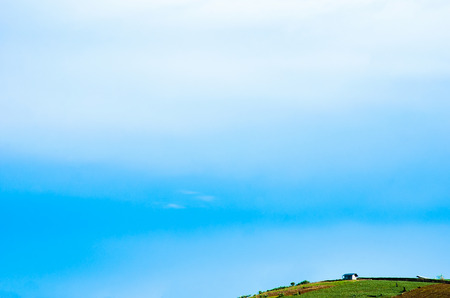 Lonely farmhouse and blue sky in evergreen hill with copy space.の写真素材