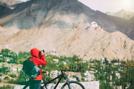 young woman taking photograph with her bicycle in the himalaya range.の写真素材