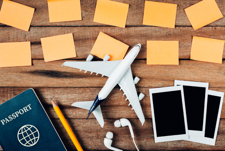 Preparation for Traveling concept and to do list, paper noted, airplane, photo frame, ear phone, pencil, passport, on vintage wooden background.の写真素材