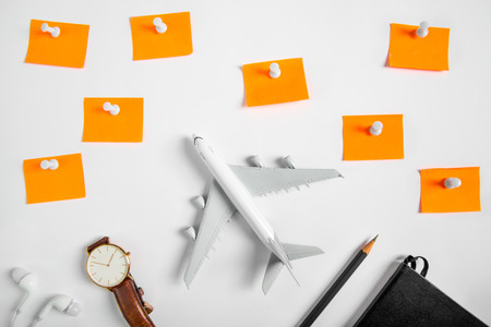 Preparation for Traveling concept and to do list, the paper noted, airplane, pencil, book, earphone, blank push pin, on white background with copy space.の写真素材