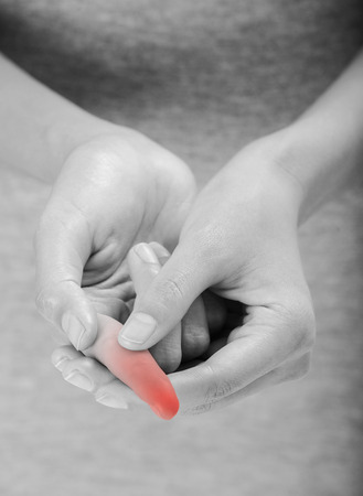 woman holding her beautiful healthy hand and massaging index finger in pain area black and white color with red highlighted.の写真素材