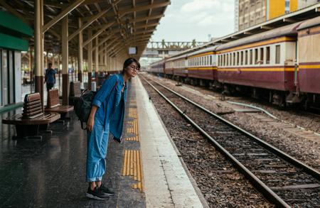 Asian woman traveler waiting train on the platform of the railway station- travel and transportation conceptの写真素材