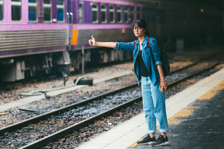 Asian woman traveler waiting train on the platform of the railway station- travel and transportation conceptの写真素材