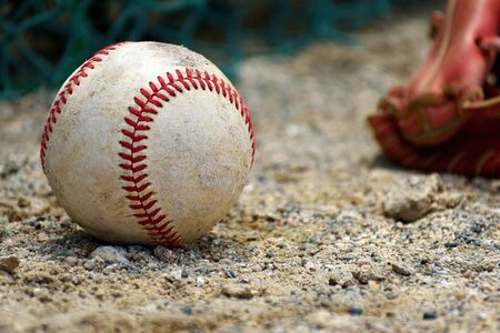 Baseball hard ball and gloves placed on the soil (close-up)