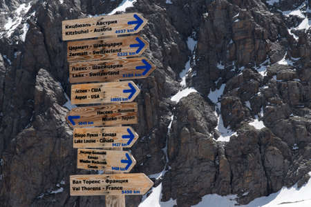 Signpost of directions to different countries in the mountains. Wooden pointers with arrows in blue...