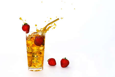 A glass with a splattering of strawberry cocktail. White background with lying strawberries. Frozen...