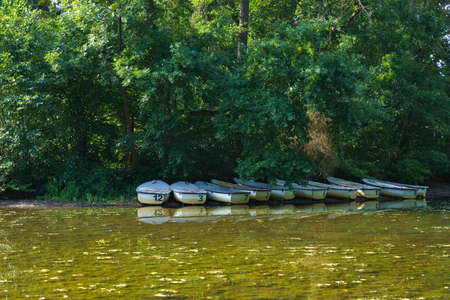 Lake with boats standing by the shore. The water is green with mud.の写真素材