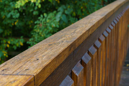 Wooden railing of the bridge. The greenery in the background is out of focus. Selected focus.の写真素材
