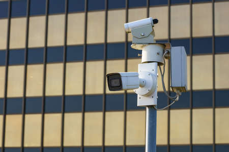 Surveillance cameras in the city in front of a modern administrative building.の写真素材