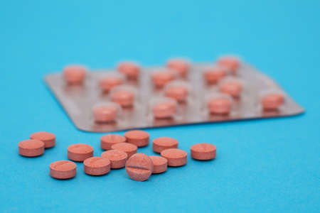 Medical pills in terracotta color on a blue background. Close-up.の写真素材