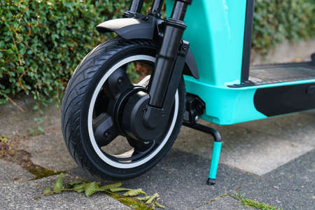 Front wheel of an electric scooter close-up. A light turquoise frame on a stand stands on the...