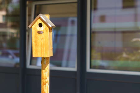 Wooden bird house in the city against the background of the building windows.