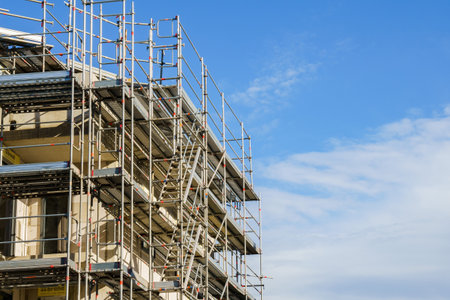 Frame of modern metal scaffolding with ladders on a building under construction on a background of...