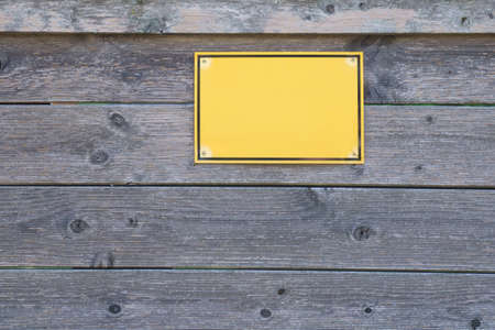 View of wooden fence with blank yellow sign ready for your text. Close up.の写真素材