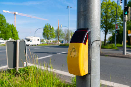 Pedestrian crossing button with blurred street. Close up yellow crossing button on the street in Germany.の写真素材