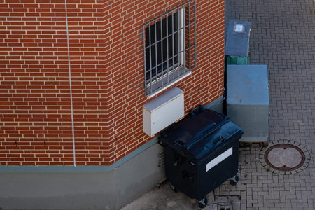 Black garbage container standing near the wall of the house. View from above.の写真素材