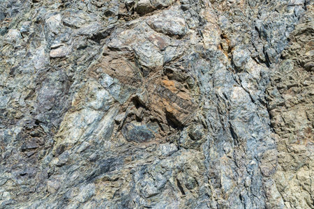 Fragment of gray rock in cracks. Close up of a mountain.