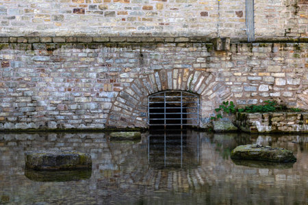 The basement curtained window of an ancient building is reflected in the water. Stone wall.の写真素材