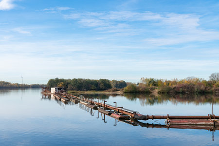 Dredger with pipeline on a large reservoir. Water landscape under a blue sky with light clouds.の写真素材