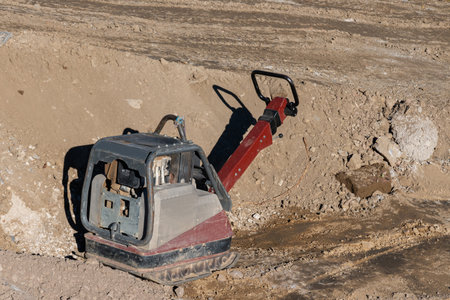 Manual diesel machine for compacting soil at a construction site.