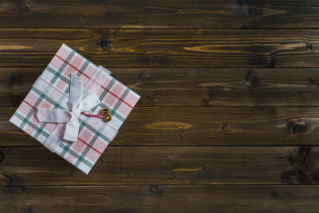 Beautiful gift checkered box with a ribbon on a dark brown table. Close-up. Copy space.の写真素材