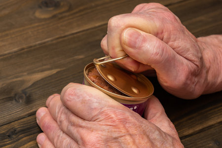 Hands of an elderly man opening a aluminium tin can. Close up.の写真素材