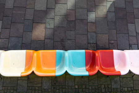 Bright multi-colored plastic seats against a gray sidewalk. View from above.の写真素材