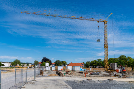 Construction site and yellow tower crane against a blue sky with light clouds.の写真素材