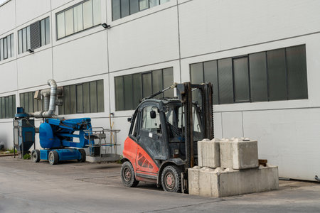 A small forklift with loaded concrete blocks stands near the building. Near the lift for people.の写真素材