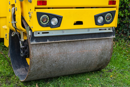 Front view of the front detail of a yellow road roller. Closeup.