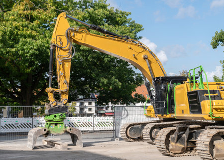 Yellow crawler excavators on a construction site. Green trees and blue sky in the background.