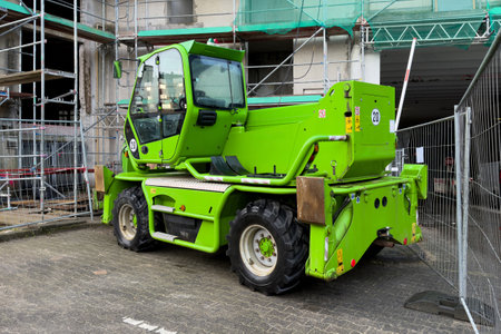 Small green construction machine against the background of a building under construction in...