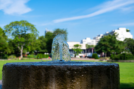 Close-up view of a small water fountain in a city park. Frozen streams of water against the blue sky.の写真素材