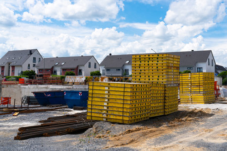 Small construction site with yellow panels and metal fittings stored on it in a residential area.