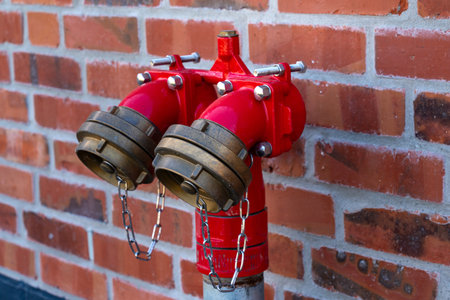 Bright red fire hydrants on a brick wall. Close up.