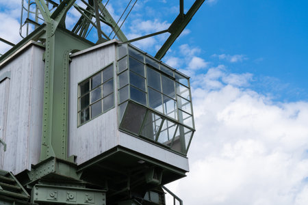 A close-up of the cab of an harbour crane with large windows, against a backdrop of a blue sky with white clouds.の写真素材