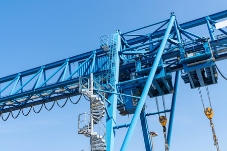 Driver's cabin and part of an overhead crane against a blue sky. Close-up.