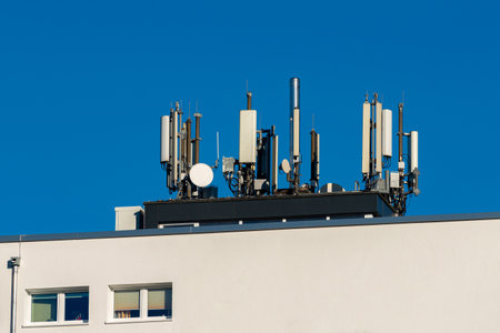 A rooftop equipped with numerous communication antennas showcases modern technology. Clear blue...