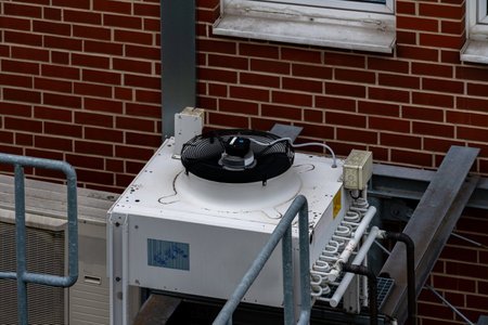 A cooling unit is positioned on the rooftop of a building, with a fan spinning to circulate air....