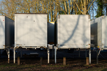 Multiple white storage containers are positioned neatly in a wooden setting. The sunlight casts...