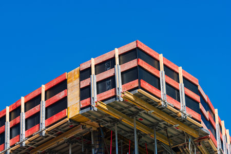 Construction site under clear blue sky with scaffolding and framework. Steel and wood materials are...