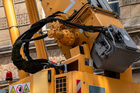 A robust machinery arm is lifted high as it engages in construction activities in an urban setting. The equipment features various warning signs and is positioned near a historical building.の写真素材