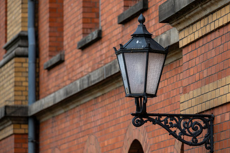 A vintage street lamp hangs elegantly against the textured brick wall of a historic building.の写真素材
