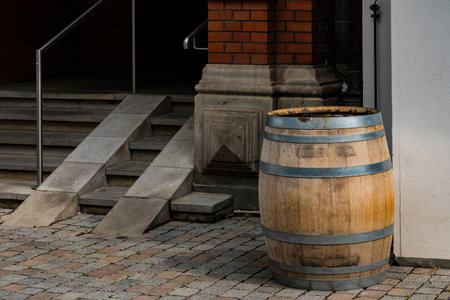 A rustic wooden barrel sits beside the entrance stairs of a building, showing its weathered exterior and metal bands.の写真素材