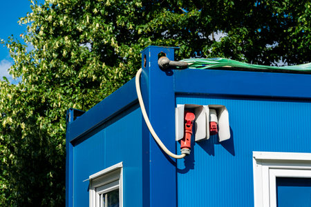 Brightly lit container features multiple power outlets mounted on its side. Surrounded by lush green...