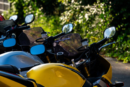 A row of motorcycles is parked along a road, shining under the sun. The vibrant colors of the bikes...