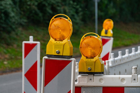 Bright yellow construction lights shine on traffic barriers, signaling a closed road zone.