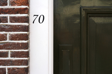 Building entrance with dark brick wall and house number in Amsterdam