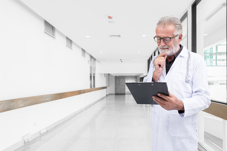Senior doctor was examine a medical record in the hospital hallwayの写真素材
