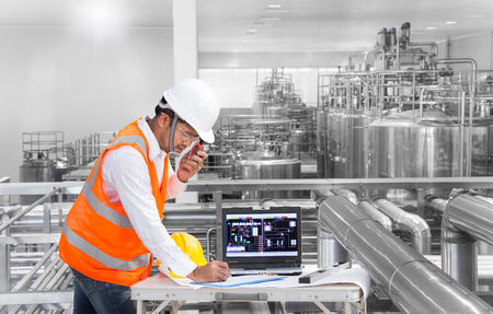 Industrial engineer checking machine status with laptop computerの写真素材